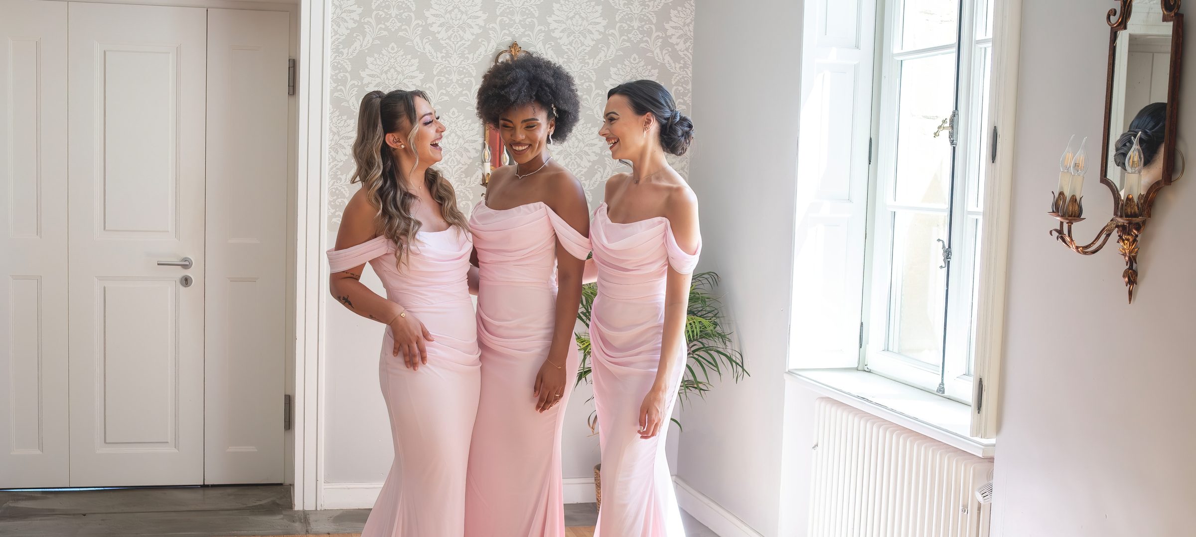 Trois demoiselles d'honneur en robes roses dans un salon
